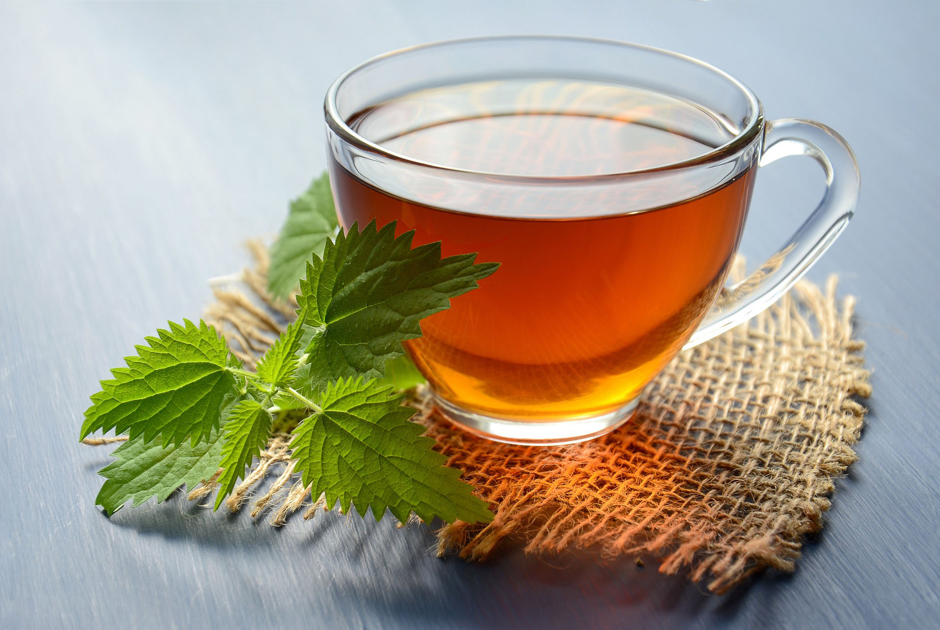 Tea in a glass cup on a burlap coaster with mint leaves